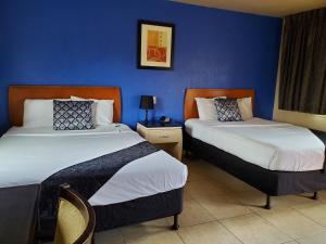 two beds in a hotel room with blue walls at PineCrest Inn & Suites in Flagstaff