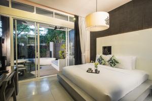 a bedroom with a large white bed and a balcony at Cher Resort SHA Plus Certified in Cha Am