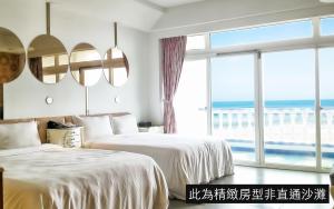 two beds in a room with a large window at White House Hot Spring Beach Resort in Wanli District