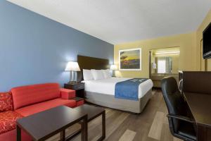 une chambre d'hôtel avec un lit et un canapé dans l'établissement Days Inn by Wyndham Greensboro Airport, à Greensboro