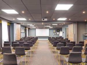 einen Konferenzraum mit Stühlen und einem weißen Bildschirm in der Unterkunft Novotel London Bridge in London
