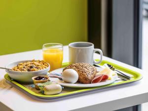 - un plateau de petit-déjeuner avec une assiette de nourriture et un verre de jus d'orange dans l'établissement ibis budget Metz Technopole, à Metz