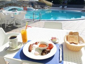 a plate of breakfast food on a table next to a pool at Kalimera Apartments in Kassiopi