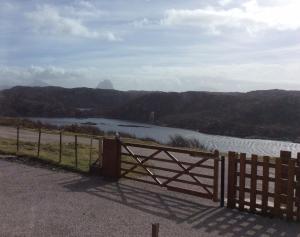 a fence with a view of a river and mountains at Achmelvich View self catering in Lochinver