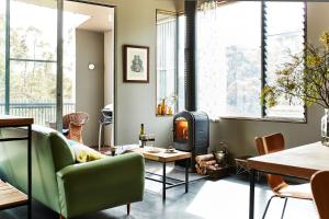 a living room with a fireplace and a green couch at Riversdale Retreat in Chewton