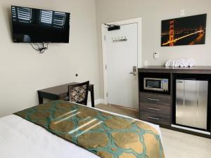 a bedroom with a bed and a desk and a tv at Bay Hotel in San Francisco