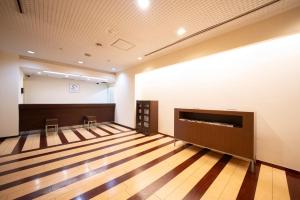 名古屋的住宿－Hotel S-plus Nagoya Sakae，一间大型空房间,铺有木地板,设有墙壁