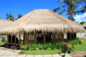 a hut with a thatched roof and palm trees at Secret Garden Bungalows in Nusa Lembongan