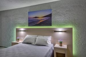 um quarto com uma cama branca e duas mesas com flores em Halaris Rooms em Ermoupoli