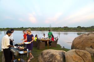 un gruppo di persone che mangia cibo a un tavolo vicino all'acqua di Cinnamon Wild Yala a Yala