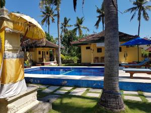 a villa with a swimming pool and a palm tree at Secret Garden Bungalows in Nusa Lembongan