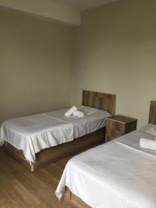 um quarto com 2 camas e lençóis brancos em Green House em Grigoleti