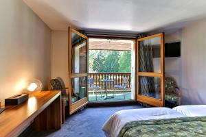 a bedroom with a bed and a view of a balcony at Le Pré de la Cure in Yvoire