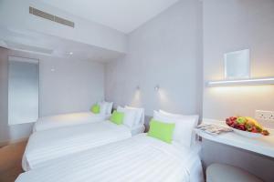 two beds in a hotel room with a bowl of fruit at Hotel Ease Mong Kok in Hong Kong