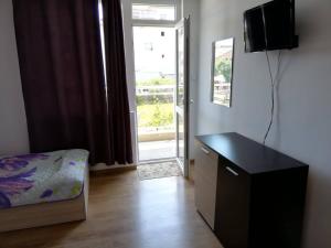 a room with a bed and a desk and a window at Къща за гости "Пердика" in Obzor