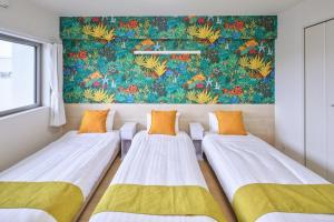 本部町にあるコンフォート・ヴィラの壁に絵画が飾られた部屋のベッド3台