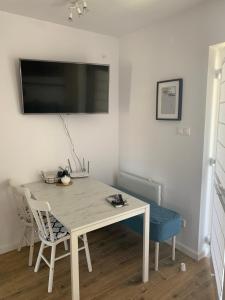 a white table and chairs with a television on a wall at apartament Wakacje w Rowach in Rowy