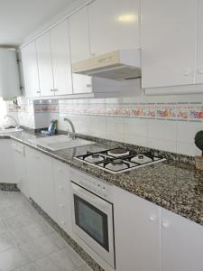 a white kitchen with a stove and a sink at FLORESTA GANDIA - Solo Familias in Playa de Gandia