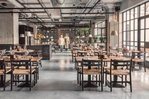 a restaurant with tables and chairs and people walking in the background at Blique by Nobis, Stockholm, a Member of Design Hotels in Stockholm