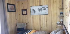 VillelaureにあるLA CABANE PERCHEEのソファ付きの木製の壁の客室で、壁に絵が飾られています。