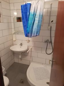a bathroom with a sink and a blue shower curtain at Resort Village T.N. Milna in Vis