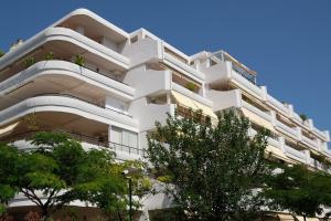 un edificio de apartamentos blanco con árboles en el primer plano en luxury modern apartment with terrace, pool and garage!, en Marbella