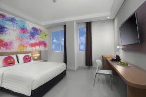 a hotel room with a bed and a desk and a tv at favehotel Hasyim Ashari Tangerang in Tangerang