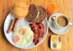 a plate of breakfast food with eggs bacon and a cup of coffee at Narawan Hotel, Hua Hin in Hua Hin