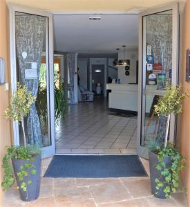 eine offene Tür eines Hauses mit Topfpflanzen in der Unterkunft Hotel Albizzia in Valras-Plage