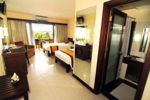 a hotel room with a bed and a living room at Nirmala Hotel Jimbaran in Jimbaran