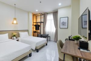 een hotelkamer met 2 bedden en een bureau bij The Akoya Saigon Hotel in Ho Chi Minh-stad