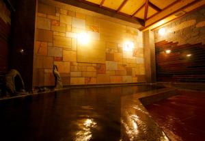 uma piscina de água num quarto com uma parede de pedra em Yugawara Retreat Goen no Mori em Yugawara