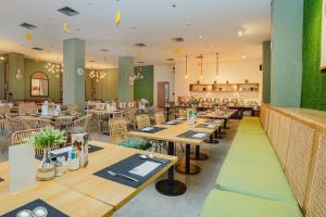 a restaurant with wooden tables and chairs and green walls at Radja Art and Boutique Hotel Simpang Lima in Semarang