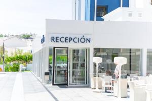 a store with white chairs and tables in front of it at Hotel Prado II in Peniscola