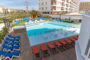 
a pool with chairs, tables, chairs and umbrellas at Hotel Prado II in Peniscola
