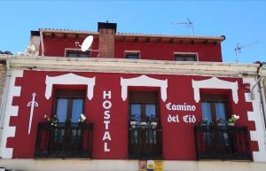 um edifício vermelho com uma cruz na lateral em Hostal Camino Del Cid em Huerta del Rey