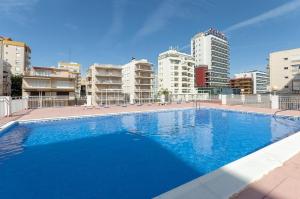 a large blue swimming pool with buildings in the background at Ondina in Gandía