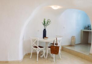 a white dining room with a table and chairs at SantoCaves in Akrotiri