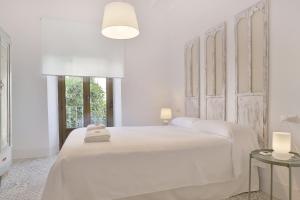 ein weißes Schlafzimmer mit einem weißen Bett und zwei Tischen in der Unterkunft Casa del Portillo-Centro Histórico in Córdoba