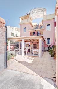 a pink house with a patio with tables and chairs at Villa Lavinia in Reggio Calabria