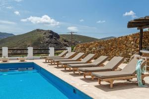 a row of lounge chairs next to a swimming pool at Mykonos Panormos Villas in Mykonos