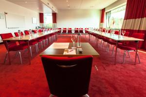 a conference room with tables and red chairs at Airport Hotel Basel - Convenient & Friendly in Basel