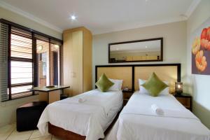 um quarto de hotel com duas camas e um espelho em Seagull Lodge em Richards Bay