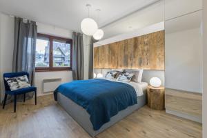 um quarto com uma cama azul e uma cadeira azul em Apartament Wierchy em Zakopane