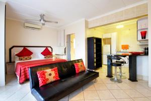 a bedroom with a bed and a black couch at Seagull Lodge in Richards Bay