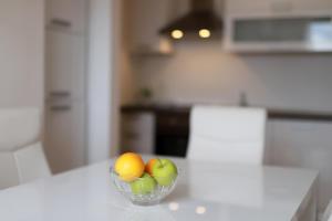 una ciotola di mele e arance sul tavolo della cucina di Apartments Galboka a Nerezine (Neresine)
