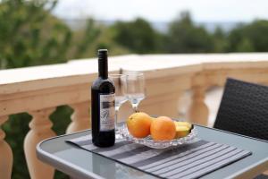 a bottle of wine and a bowl of fruit on a table at Apartments Galboka in Nerezine