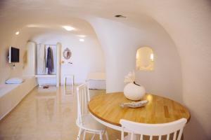 a dining room with a wooden table and white chairs at SantoCaves in Akrotiri