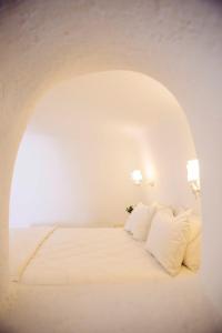 a bedroom with a bed with white sheets and pillows at SantoCaves in Akrotiri