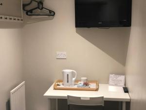 Zimmer mit einem Tisch und einem TV an der Wand in der Unterkunft The Fulwich Hotel in Dartford